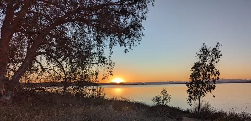 Sunset over Lake Skinner seen from a dirt shoreline trail